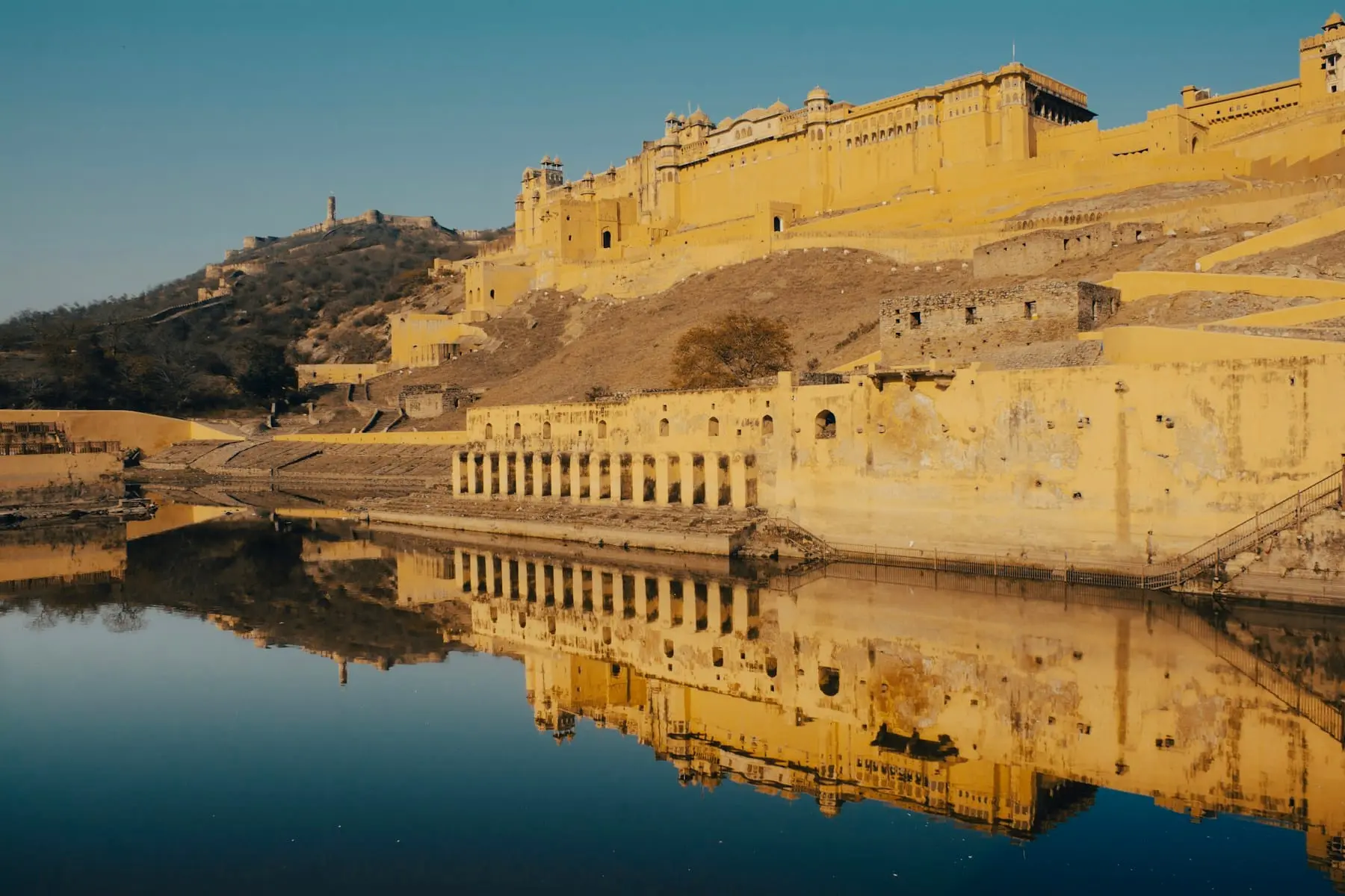 Amber Fort's sandstone walls on the hillside, reflected in the calm water of Maota Lake